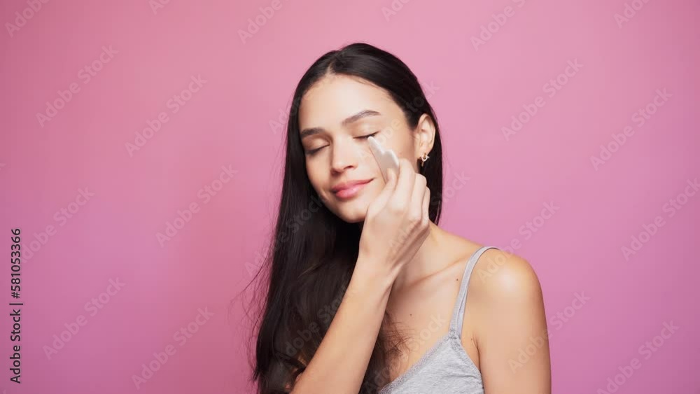 Smiling woman with massaging her face with a wasa stone Smiling woman with massaging her face with a wasa stone