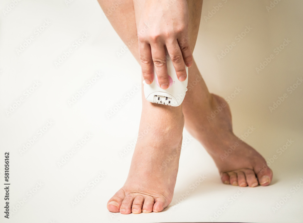 girl shaving her legs with an epilator close-up girl shaving her legs with an epilator close-up