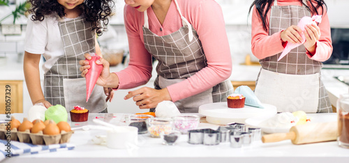 Portrait of enjoy happy love asian family mother and little toddler asian girl daughter child having fun cooking together with dough for homemade bake cookie and cake ingredient on table in kitchen