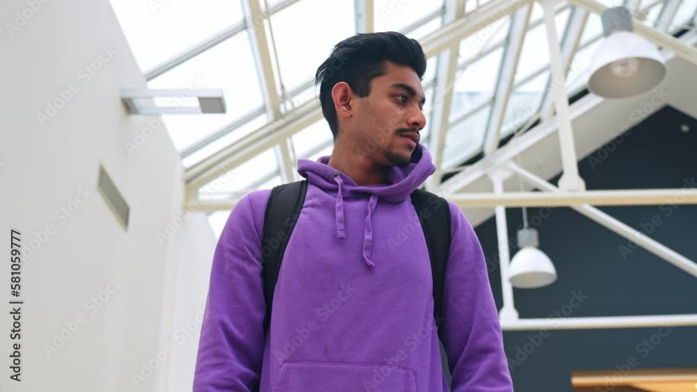 Low angle closeup portrait of young bearded man going down stairs, shopping mall