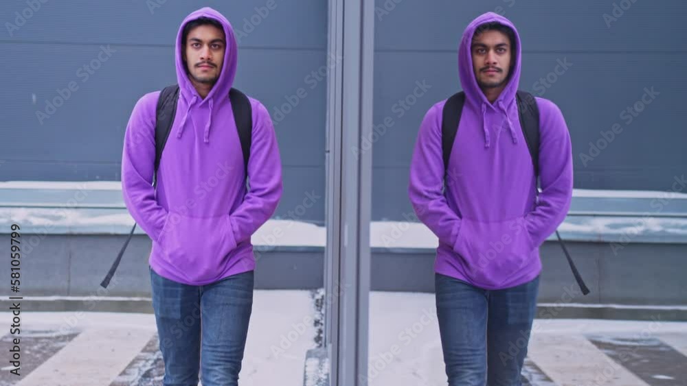 Slow motion shot of man wearing purple hoddie walking next to glass window