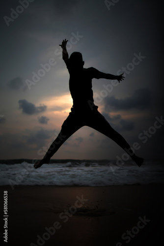 silhouette of people jumping on the beach at sunset