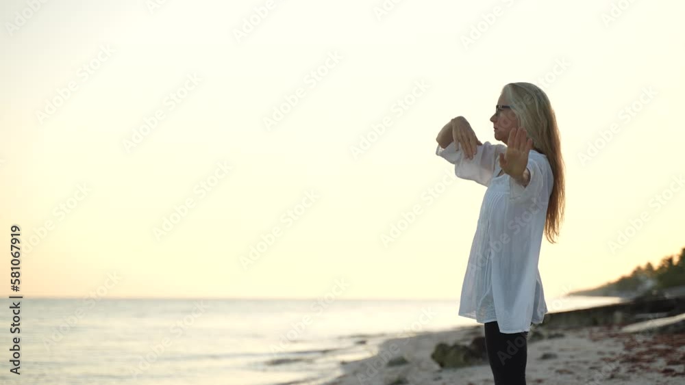 Fit mature senior woman stretching practicing yoga and dancing during the morning sunrise on the beach. Fit mature senior woman stretching practicing yoga and dancing during the morning sunrise on the beach.