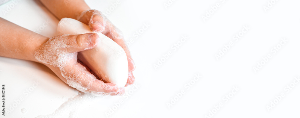 Naklejka premium Hand washing with soap. a small child is holding soap in his hands . Isolate on a white background. banner. the concept of cleanliness and hygiene