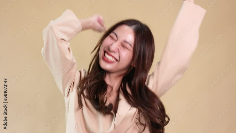 Excited screaming young Asian woman standing and looking at camera isolated over yellow beige color background. Surprise and hearing good news concept Excited screaming young Asian woman standing and looking at camera isolated over yellow beige color background. Surprise and hearing good news concept