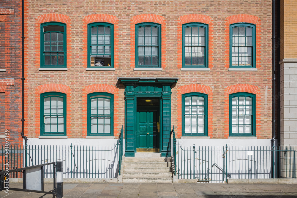 Front elevation of a Georgian style terraced house in London with green door and window frames