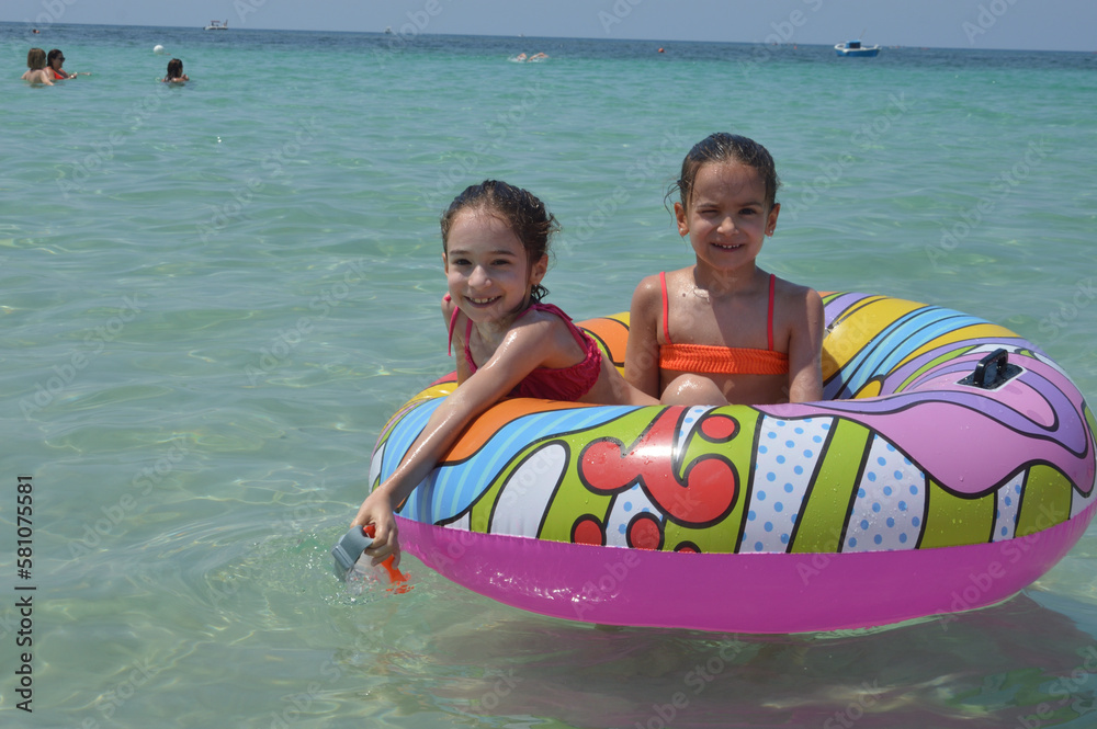 Obraz premium Sorelle gemelle al mare sul materassino.