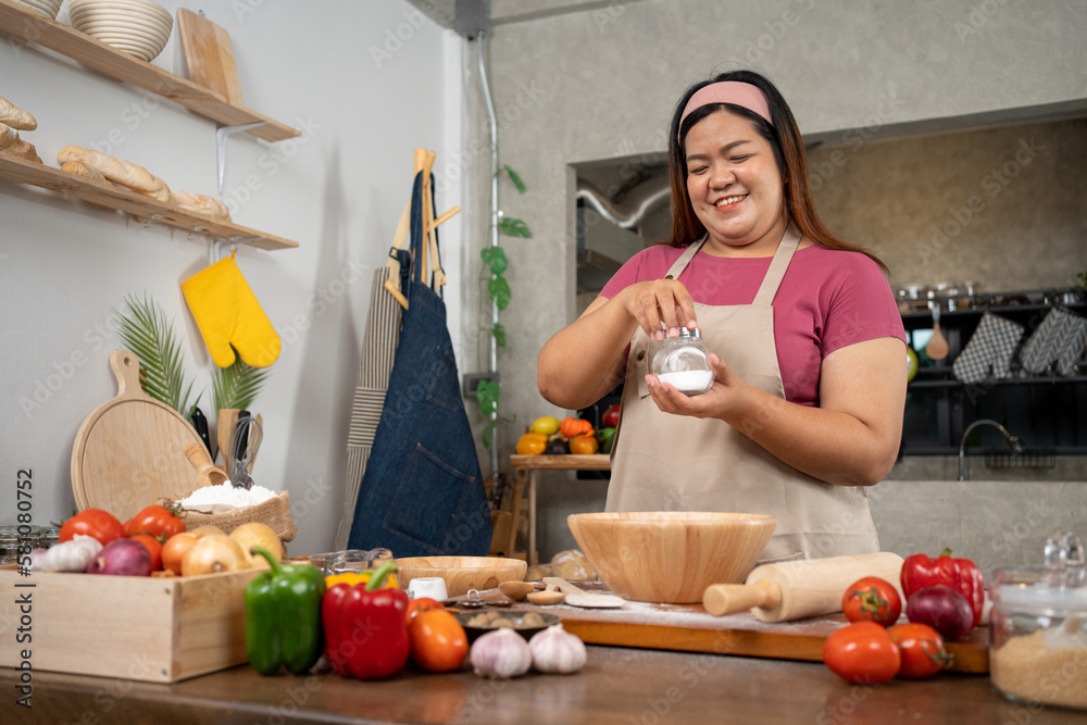 Portrait of obese woman cooking pizza in the kitchen, Raw pizza in the hands of a housewife. Homemade pizza cooking in the kitchen at home. Learning how to make yummy pizza dinner lunch