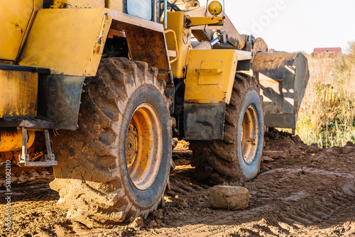 A large yellow wheel loader aligns ground for a new building. Land preparation for the auction or sale. Plot leveling and adding sand for construction. Banner. Copy space. Special transport. Closeup