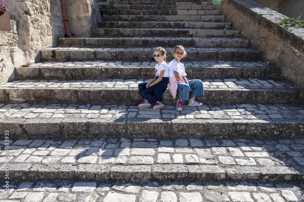 Ritratto di due sorelle gemelle di 8 anni sedute su una scalinata.