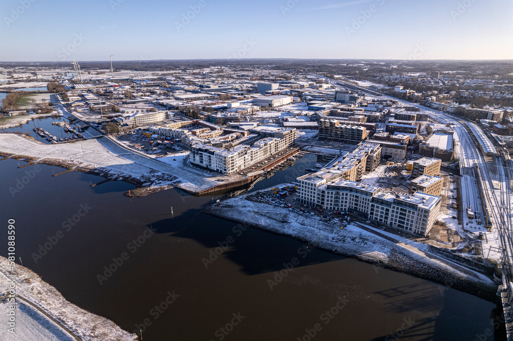 Noorderhaven neighbourhood at river IJssel with white floodplains of Dutch town Zutphen, The Netherlands. Aerial cityscape after a snowstorm. Climate and weather condition concept