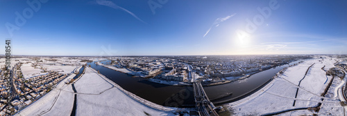 Cinematic aerial of Drogenapstoren in medieval Hanseatic Dutch tower town Zutphen in the Netherlands with historic heritage buildings covered in snow in the background