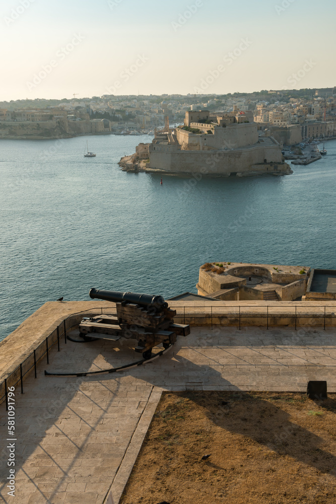 Malta, Valletta, August 2019. Ancient cannon against the backdrop of a large harbor.