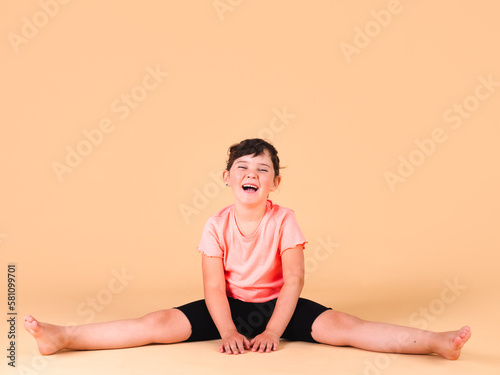 elementary girl exercising on beige background © 23_stockphotography