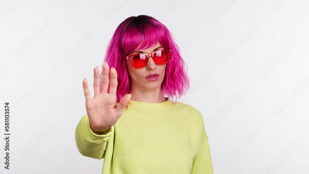 Woman showing no gesture, stop, disagreement end expression. Serious lady, pink hair, hipster in sunglasses, no way ignore finish emotion. Body language concept, studio isolated on white background Woman showing no gesture, stop, disagreement end expression. Serious lady, pink hair, hipster in sunglasses, no way ignore finish emotion. Body language concept, studio isolated on white background