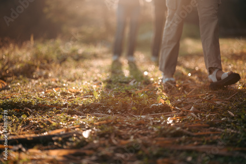 Woman walking in meadow at sunrise, closeup to a leg of female family in the morning at natural park or forest trail, feeling of relaxation and happy time, Young woman hiking and going sport camping