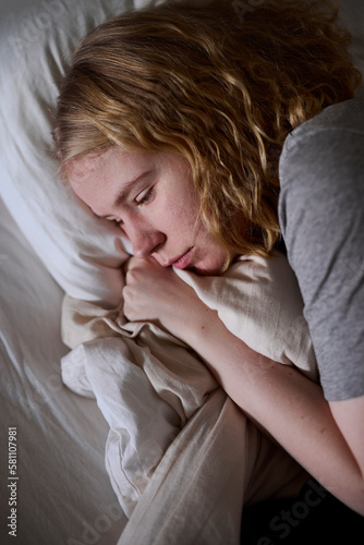 Crying young woman lying in bed photo