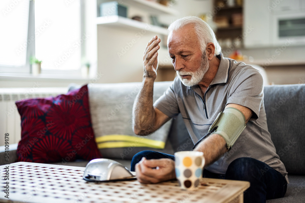 Senior checking his blood pressure. Senior man examining blood pressure in bedroom at home during the day. Senior checking his blood pressure. Senior man examining blood pressure in bedroom at home during the day.
