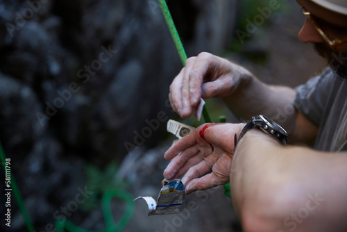 Rock climber putting plaster on injured hand photo