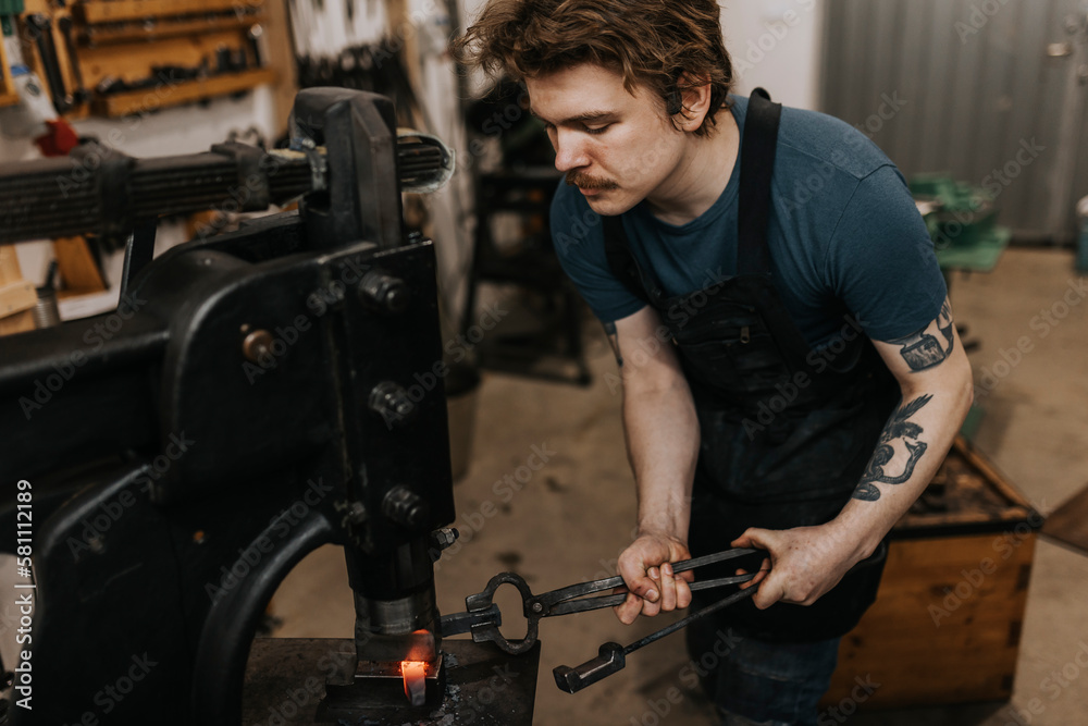 Male blacksmith forging metal in workshop Male blacksmith forging metal in workshop