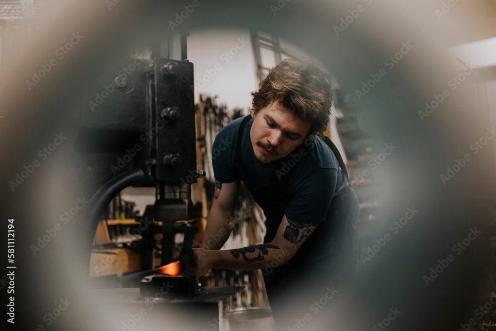 Male blacksmith forging metal in workshop Male blacksmith forging metal in workshop