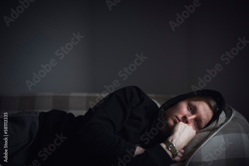 Sad man facing depression lying in bed photo