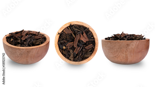 Dry fermented tea leaves with cinnamon in a wooden bowl on a white background.