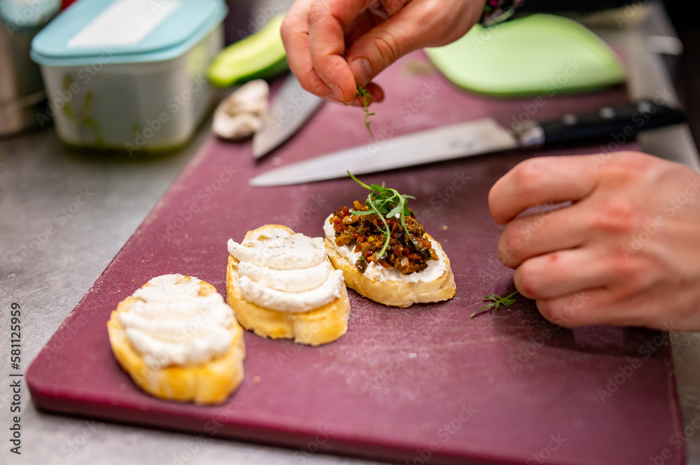 man chef hand cooking Bruschetta with tapenade and cream cheese on restaurant kitchen