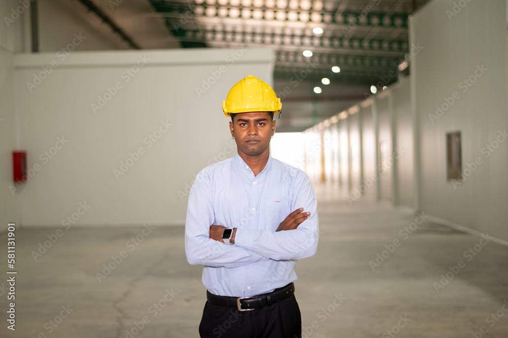 Indian worker standing confident in factory background Indian worker standing confident in factory background