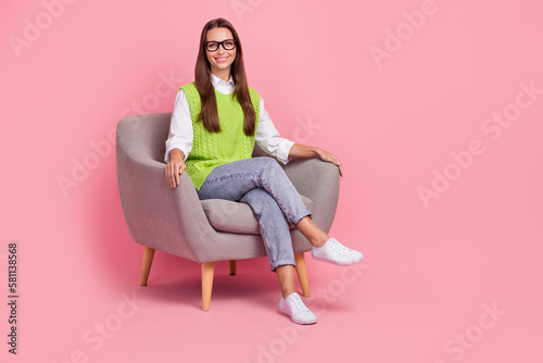 Full size photo of friendly professional psychology specialist woman waistcoat jeans sit on armchair isolated on pink color background