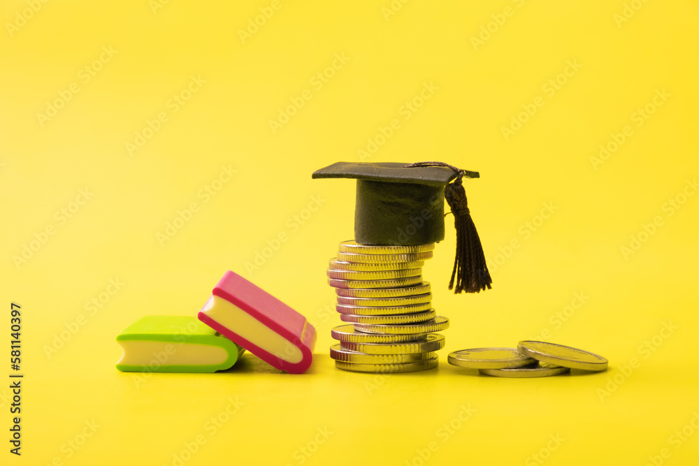 Graduated cap with coins on yellow background. Savings for education or financial literacy concept - obrazy, fototapety, plakaty 