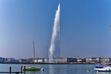 Beautiful and famous jet d'eau water fountain at Lake Geneva at Swiss City of Geneva with skyline in the background on a sunny winter day. Photo taken March 5th, 2023, Geneva, Switzerland.