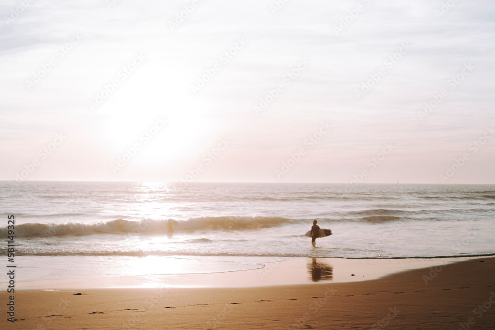 Silueta de surfista entrando en el agua al atardecer en playas de andalucia