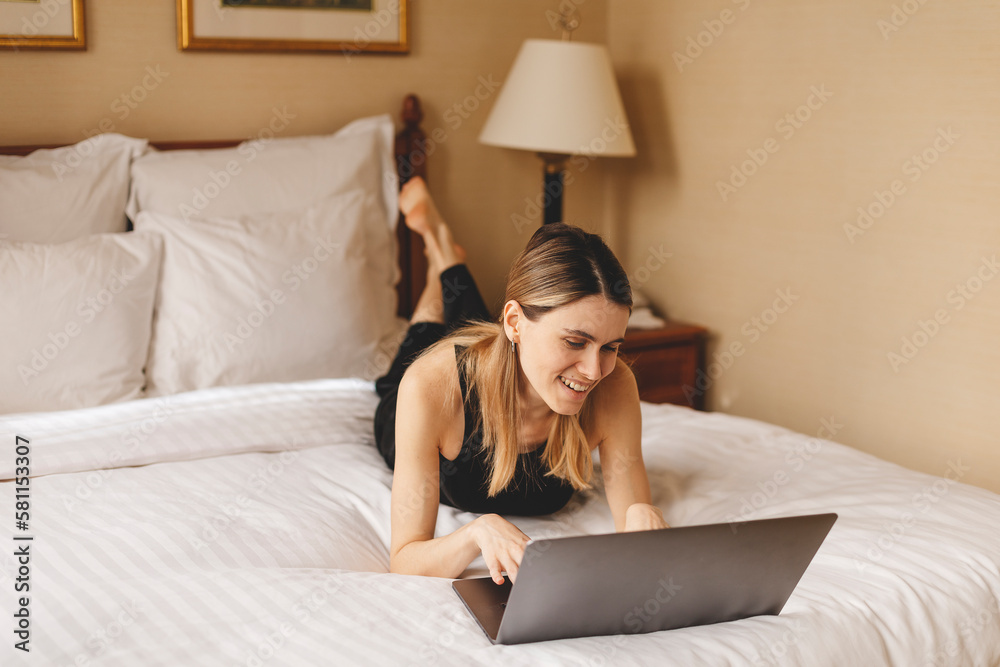 Happy woman using laptop making video call lying on bed at home in bedroom. Modern communication. Freelancer lady browsing internet. Technology and freelance. Happy woman using laptop making video call lying on bed at home in bedroom. Modern communication. Freelancer lady browsing internet. Technology and freelance.