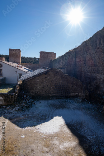 Muro del pueblo madrileño de Buitrago de Lozoya con una pequeña casa nevada al lado bajo un cielo azul soleado.