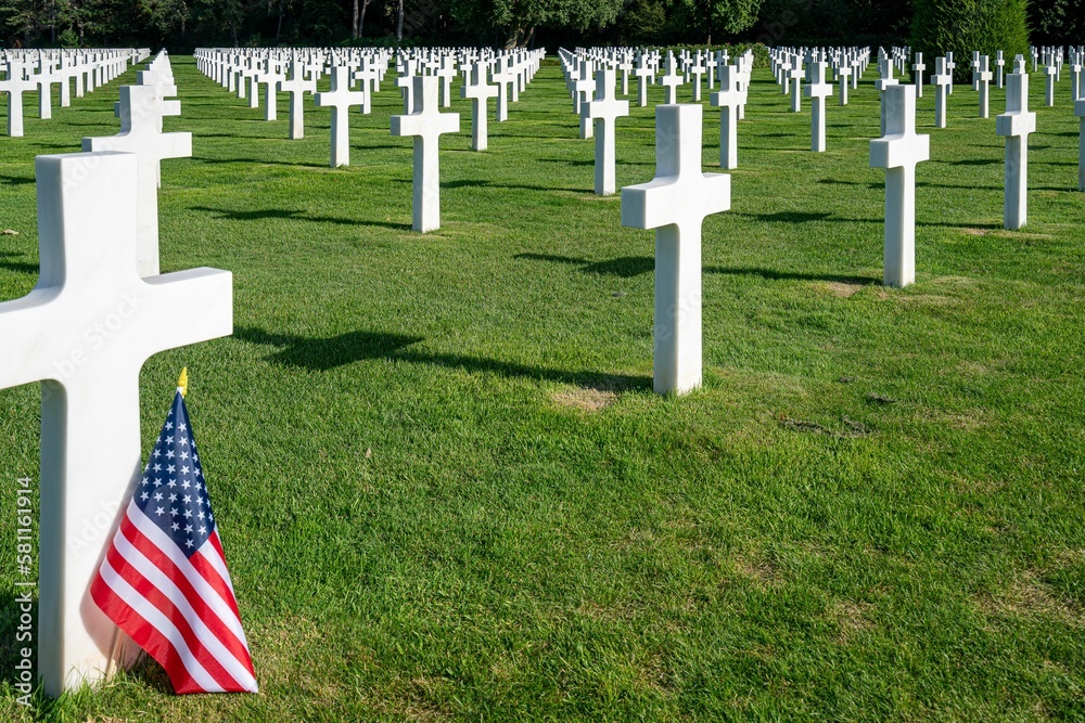 Obraz premium American flag standing at the gravestone of a killed soldier at the war cemetery in Normandy