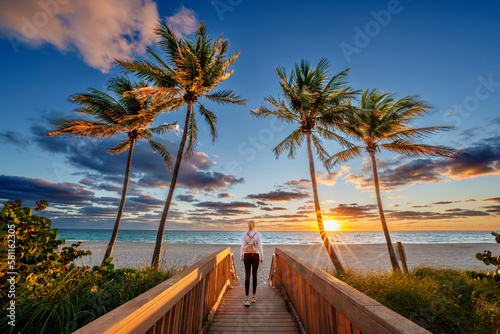 Fototapeta Naklejka Na Ścianę i Meble -  Woman enjoying Sunrise,walking to the Beach,taking Photos with the Phone,.Hollywood Beach,Hollywood,Miami .Floridas East Coast.Miami Beach,Miami Florida USA
