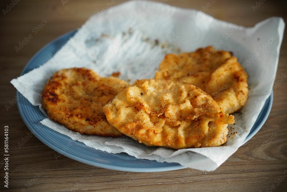 Closeup of deep-fried chicken breast served on a blue plate Closeup of deep-fried chicken breast served on a blue plate