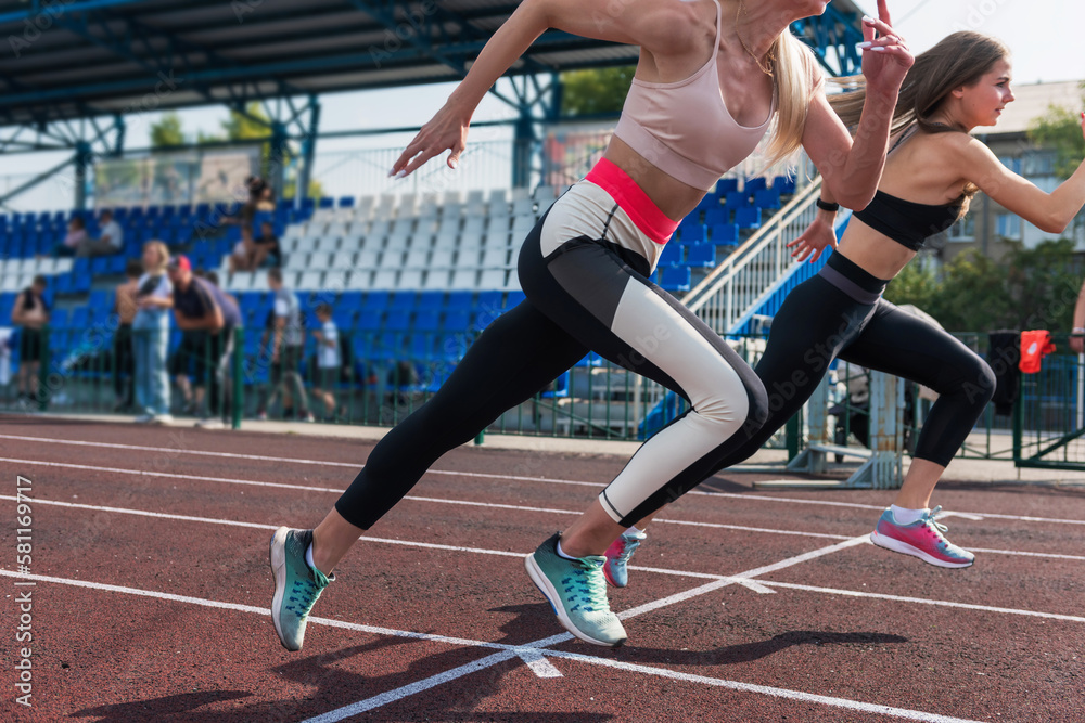 Fototapeta premium Two athlete young woman runnner on the start at the stadium outdoors