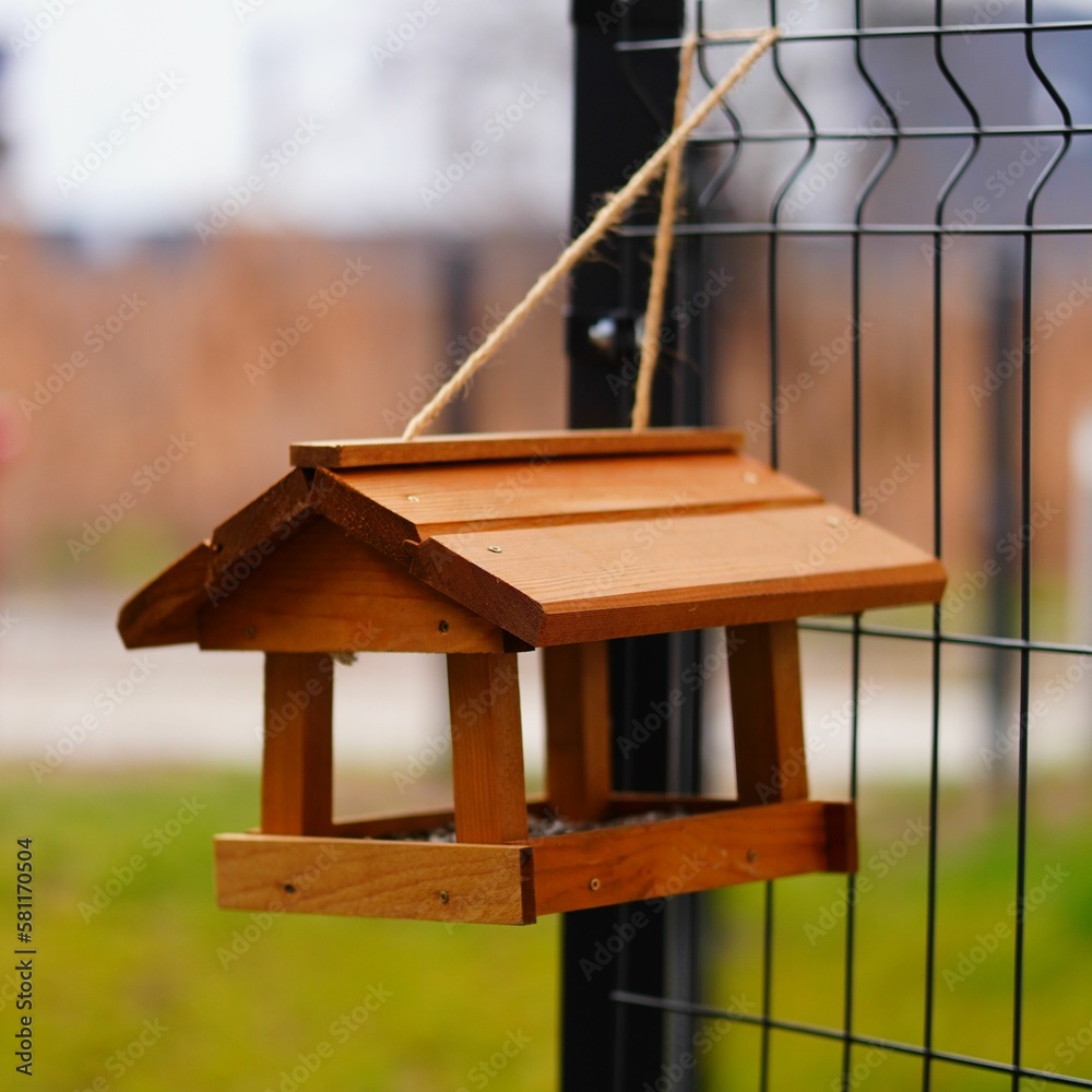 Rustic birdhouse hanging from the back of a weathered wire fence in a rural outdoor setting Rustic birdhouse hanging from the back of a weathered wire fence in a rural outdoor setting