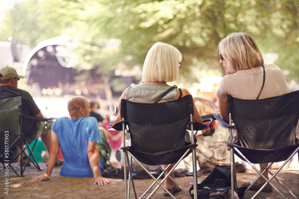 Peace, love and music. Rearview shot of two friends sitting together at an outdoor festival. Peace, love and music. Rearview shot of two friends sitting together at an outdoor festival.