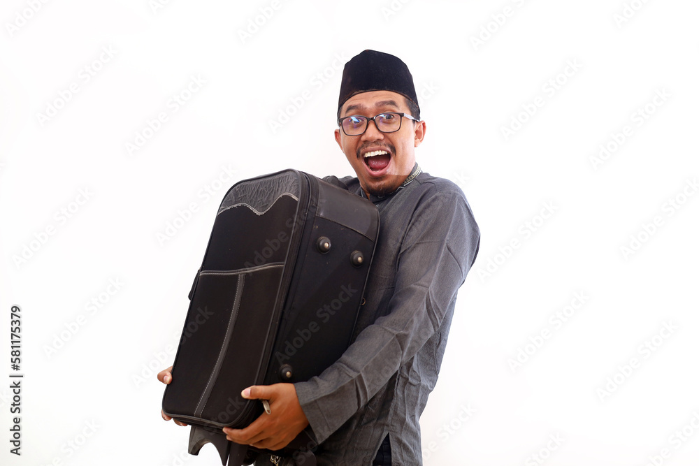 Excited Asian muslim man holding suitcase. Homecoming and ramada