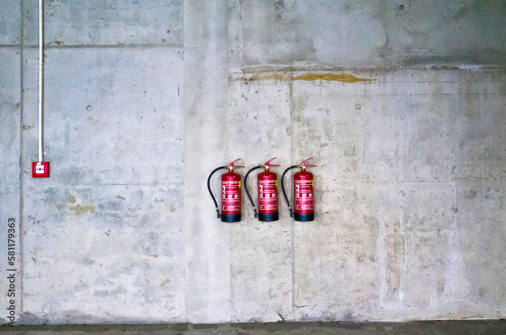 grey industrial wall with red fire extinguishers grey industrial wall with red fire extinguishers