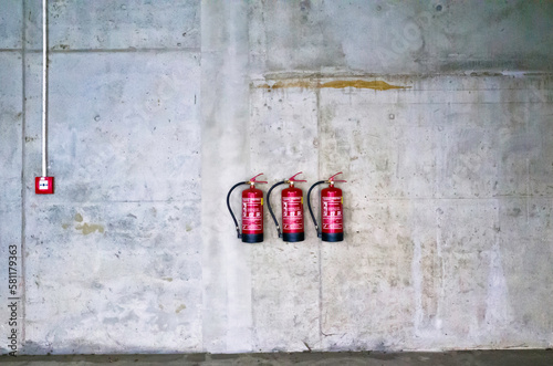 grey industrial wall with red fire extinguishers 