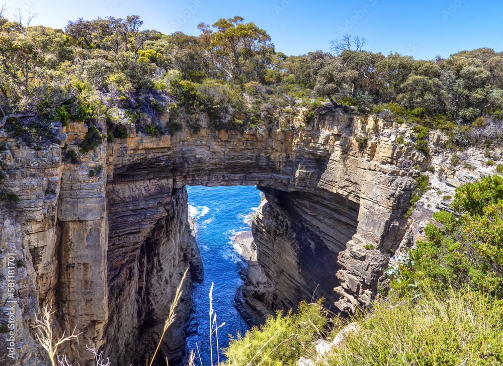 A panorama of the Tasman or Tasmans Arch, a natural rock bridge over the sea at Eaglehawk Neck, near Port Arthur, Tasmania. This towering arch is covered with a eucalyptus forest.