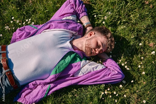 Young blond male laying on a green meadow with a relaxed expression