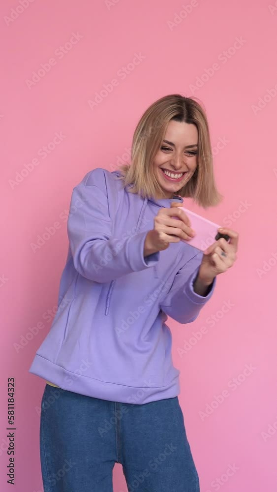 Smiling woman playing games with her smartphone. Vertical video. Smiling woman playing games with her smartphone. Vertical video.