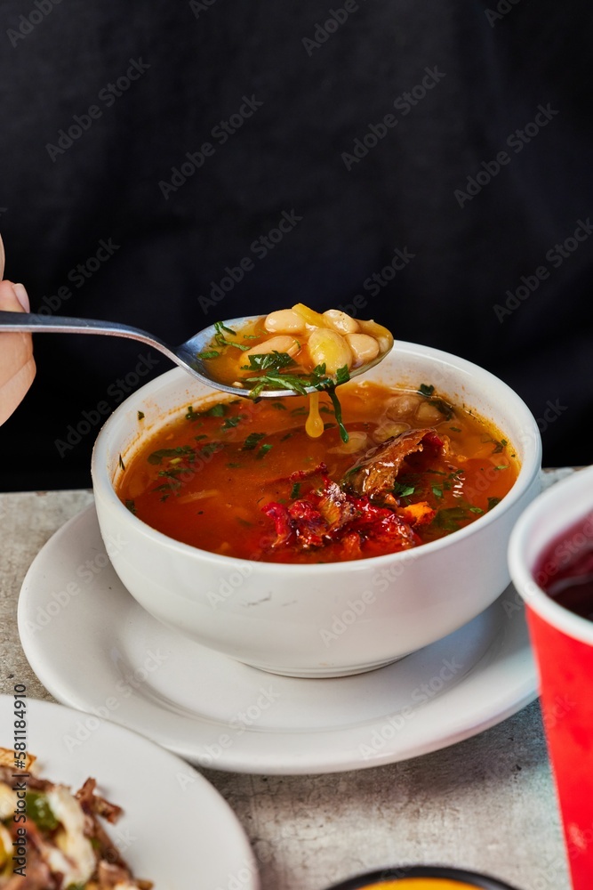 Vertical closeup of a person tasting a soup with beans Vertical closeup of a person tasting a soup with beans