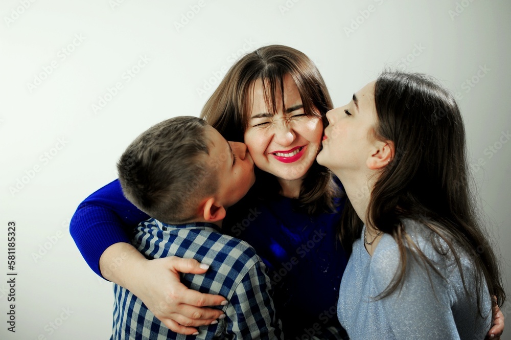 Happy family children kiss mom from two sides. Sons show freedom love Loving family portrait Children from 2 sides kisses mom Happy family children kiss mom from two sides. Sons show freedom love Loving family portrait Children from 2 sides kisses mom