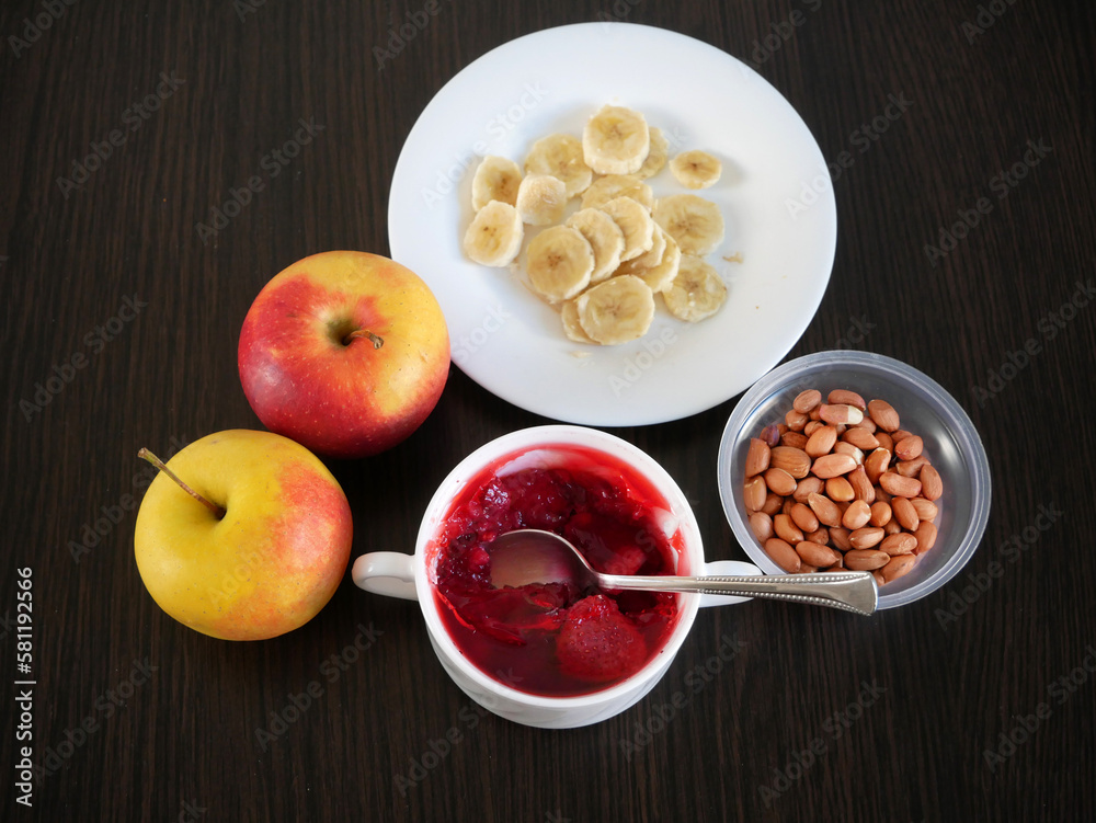 Banana, fruit jelly, milk dessert with low calories, apples in plates on dark wooden background, healthy breakfast, anti cholesterol diet Banana, fruit jelly, milk dessert with low calories, apples in plates on dark wooden background, healthy breakfast, anti cholesterol diet